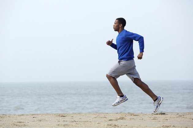 Young athletic man running at the beach
