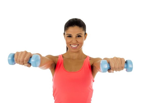 young attractive happy latin woman in sport clothes with beautiful smile holding weight dumbbell doing fitness workout isolated on white background in healthy lifestyle concept