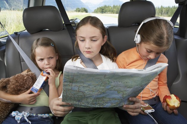 Three girls (6-8 years) sitting on rear seat of car during road trip