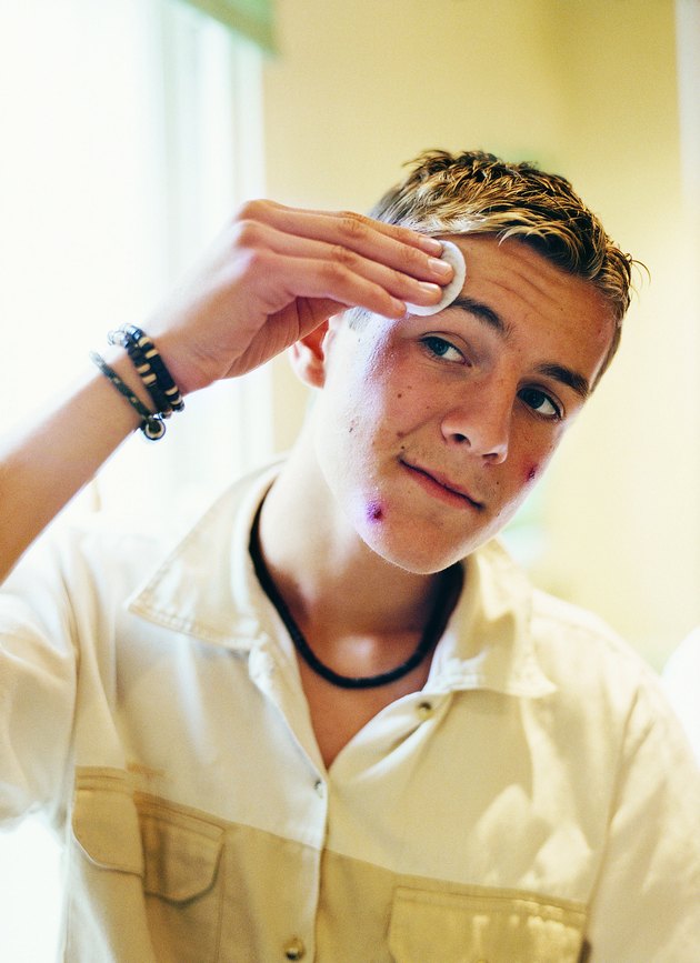 Portrait of a Male Teenager Cleaning his Acne