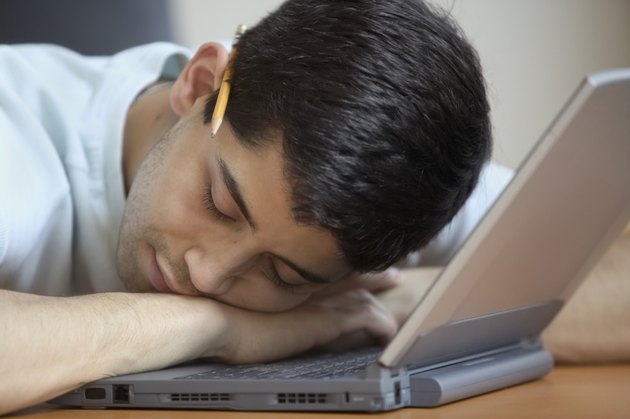 Close-up of a young man resting on a laptop