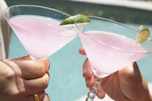 Close-up of two people's hands toasting with martini glasses