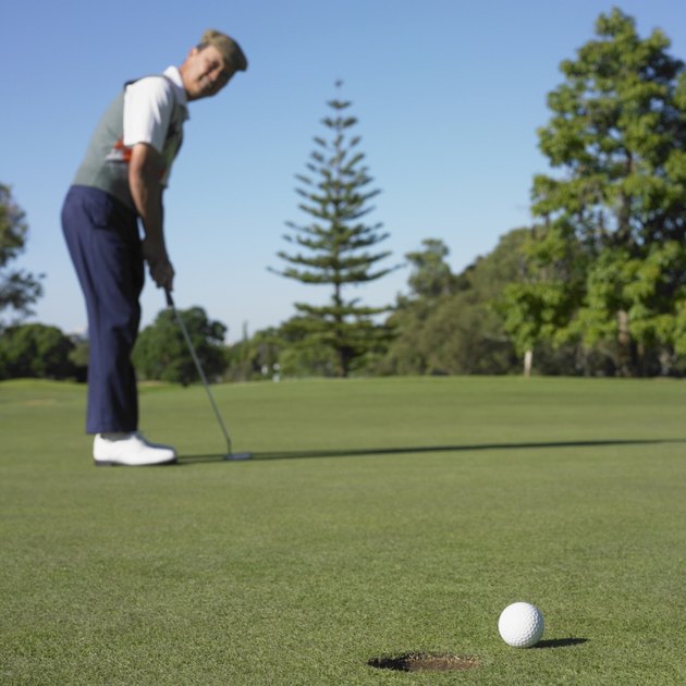 Asian man putting on golf course