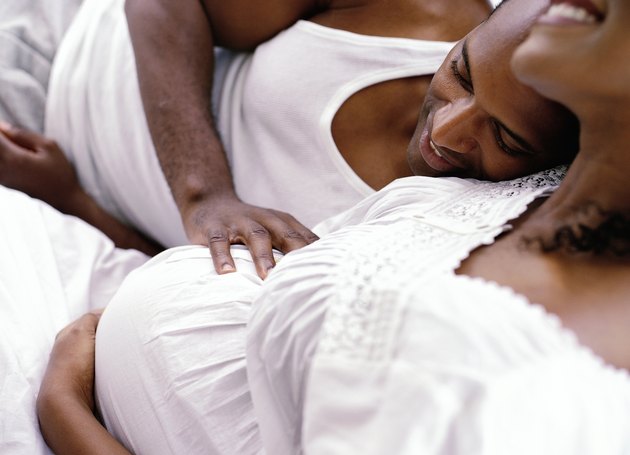 side profile close-up of a man lying close to his pregnant wife
