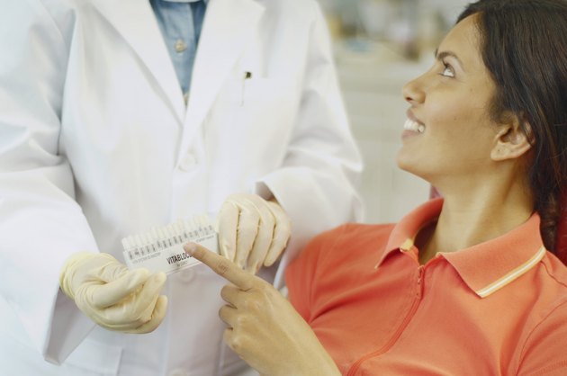 Dental patient choosing tooth color sample from dentist