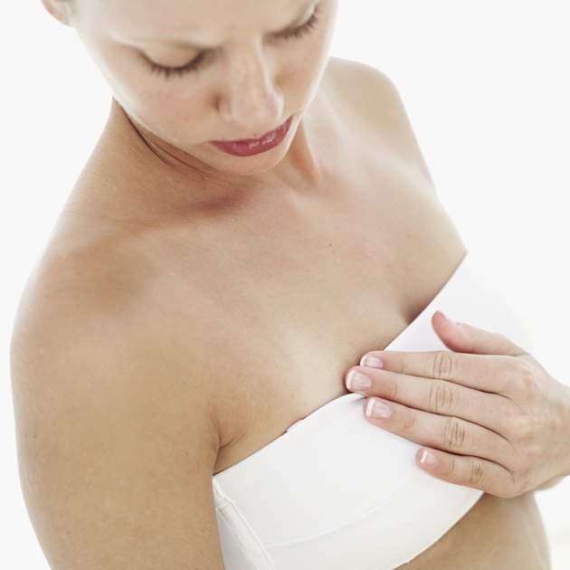 Close-up of a young woman touching and looking at her breast