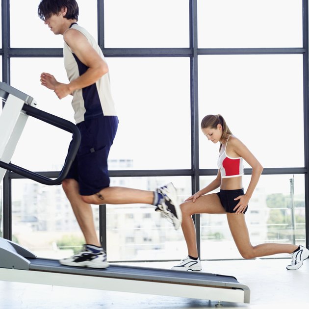 Young man running on a treadmill beside a young woman doing lunges
