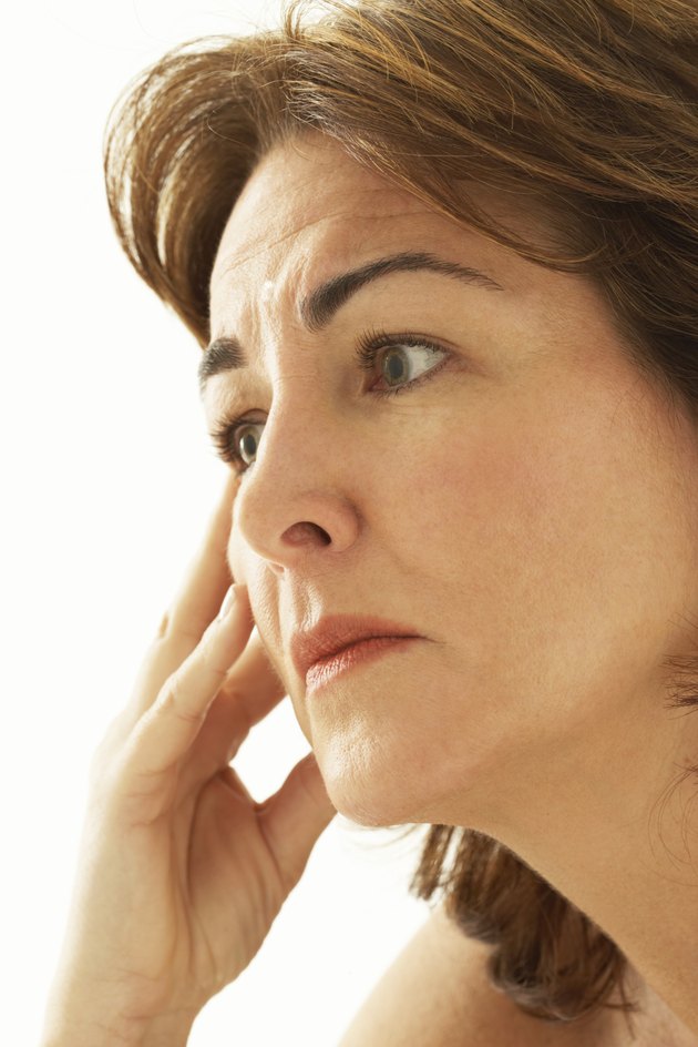 Mature woman with hand on face, side view, close-up