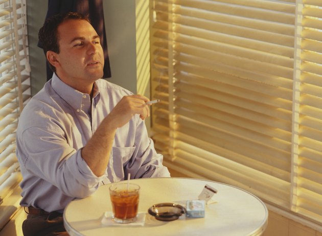 Man smoking, drinking in bar at table