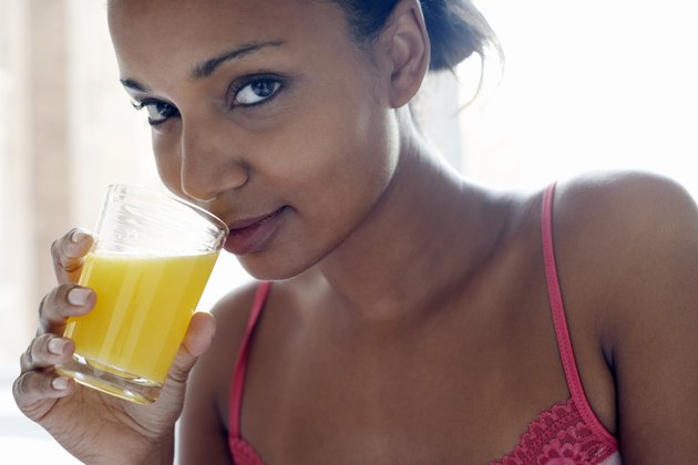 Young woman drinking glass of juice, close-up, portrait
