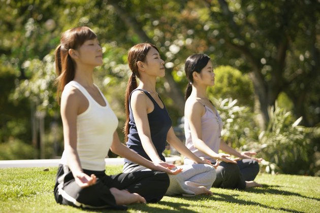 Three young women meditating, side view