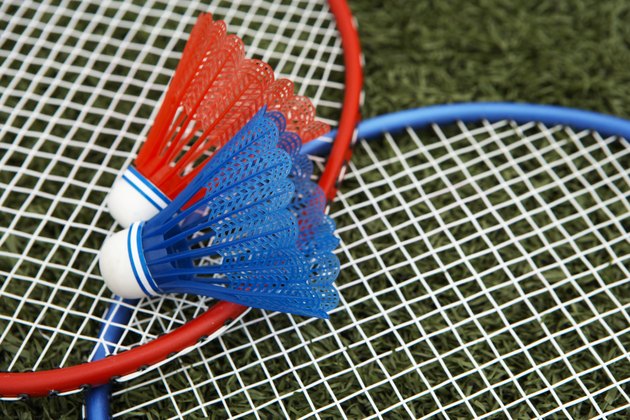 Two shuttlecocks atop badminton rackets (focus on shuttlecock)