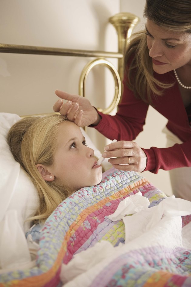 Girl with fever lying down in bed indoors