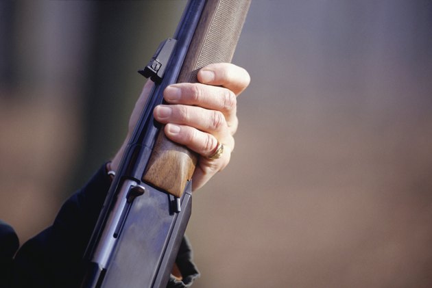 Man holding shotgun, mid section, close-up of hand