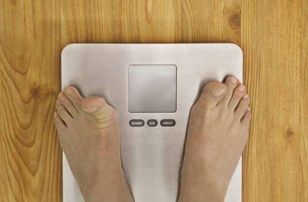 Person standing on weighing scale, low section, view from above