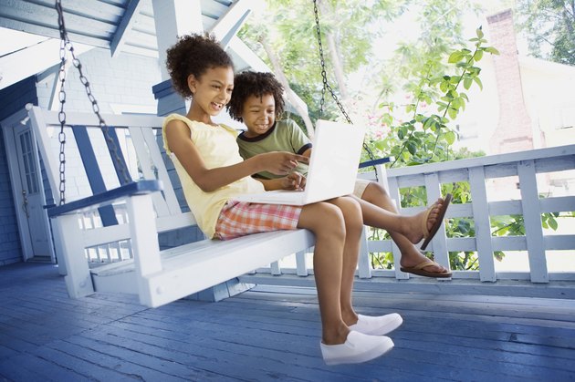 Brother and sister with laptop computer outdoors