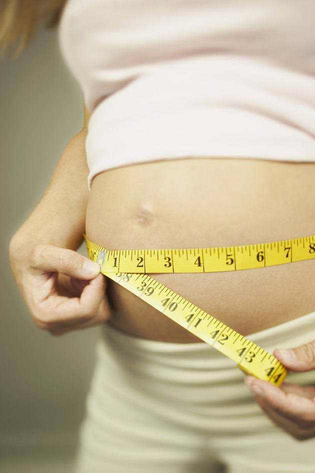 Cropped pregnant woman measuring waist