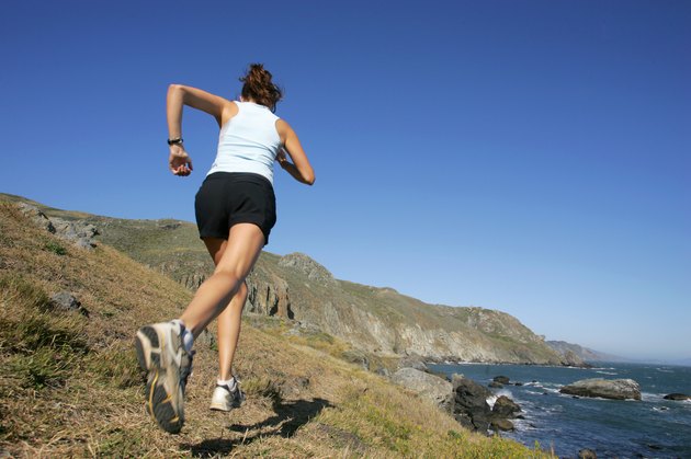 Woman running along coastline, California, USA