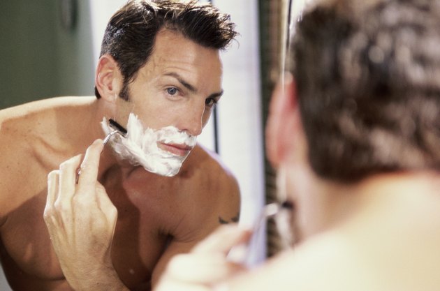 Close-up of a young man shaving in the bathroom
