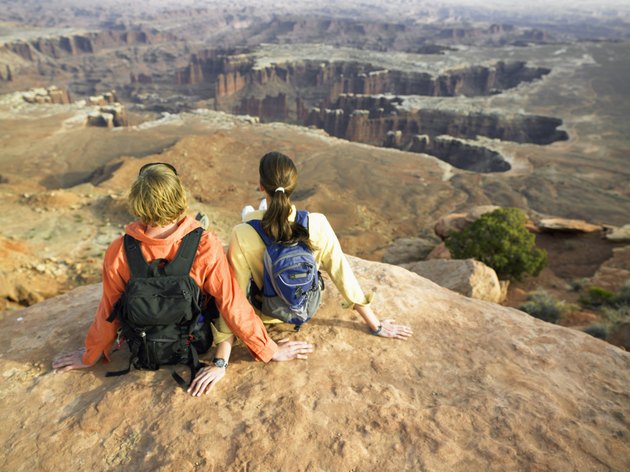 Young couple with backpacks sitting on rock