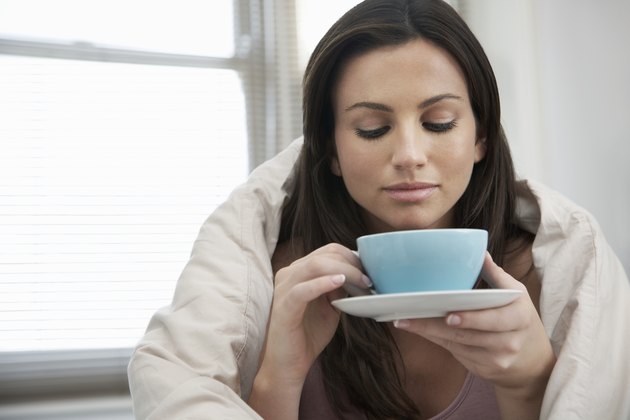 Young woman drinking tea in bed