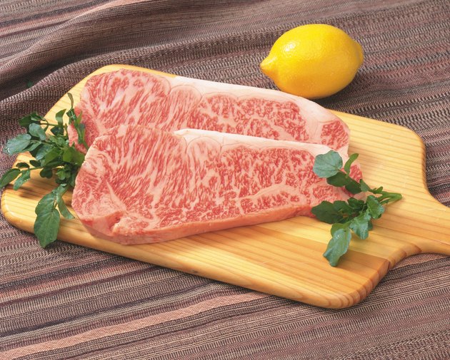 Sir Loin steaks on cutting board with lemon, high angle view, close up