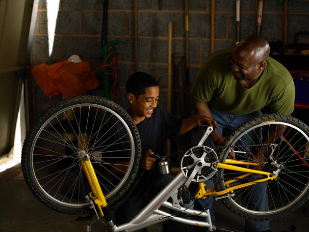Father and teenager oiling bicycle chain
