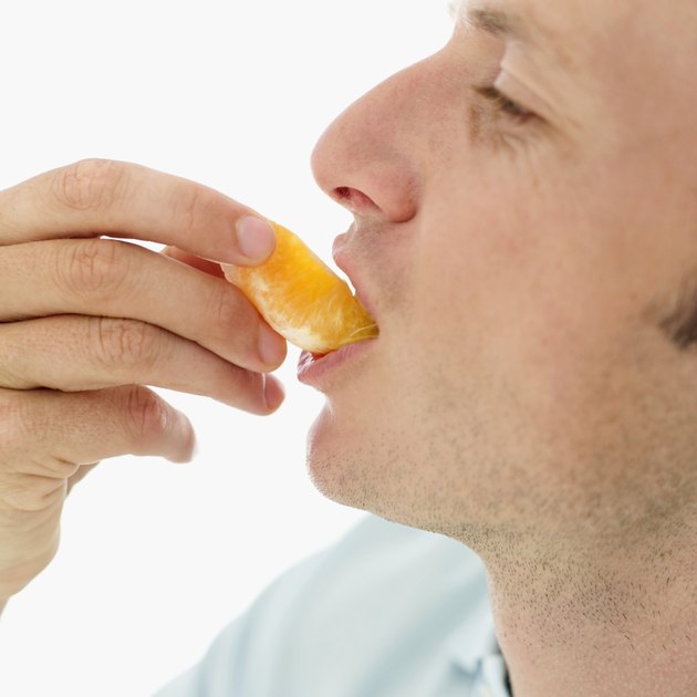 Young man eating a piece of orange