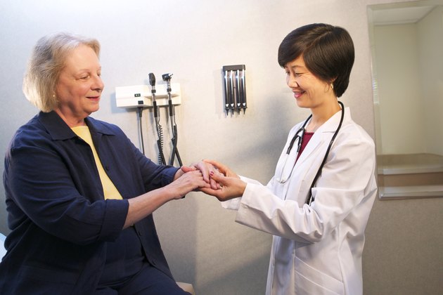 A doctor examines a mature woman's arm in the doctor's office