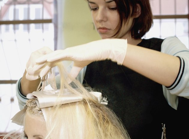 Close-up of a female hairdresser dyeing a mid adult woman's hair