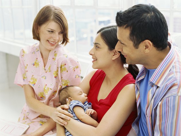 mid adult woman smiling and looking at a mid adult couple holding their son