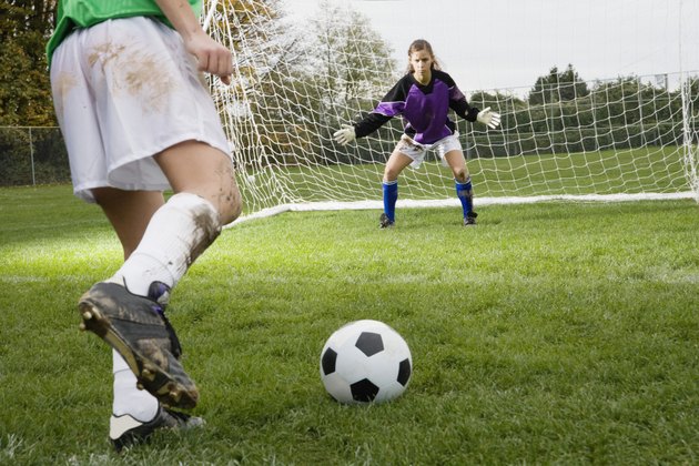 Girl kicking soccer ball toward goal