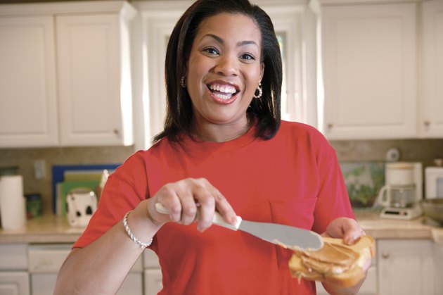 Woman spreading peanut butter on bread