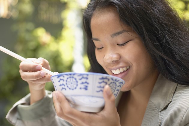 Asian woman eating with chopsticks