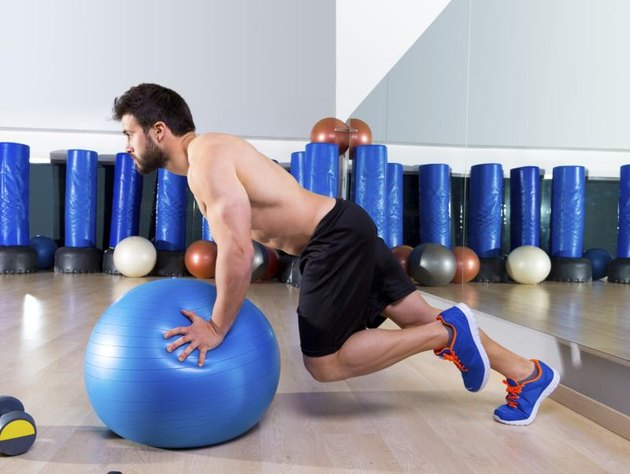 Fitball abdominal push ups Swiss ball man one single leg pushup at fitness gym