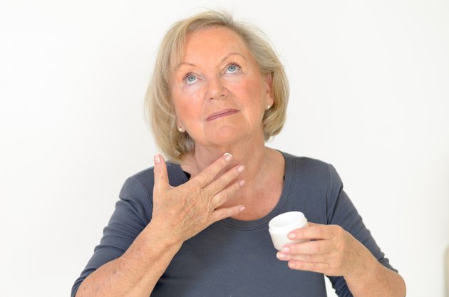 Attractive middle-aged woman applying creme
