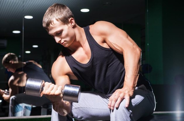 Young bodybuilder doing exercise on biceps with dumbbell