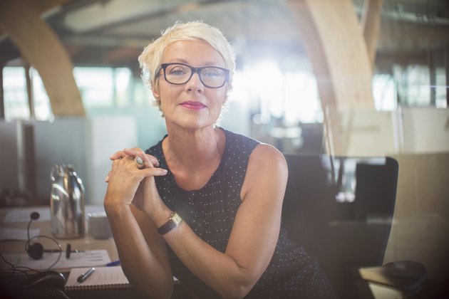 Businesswoman sitting with hands clasped at office desk