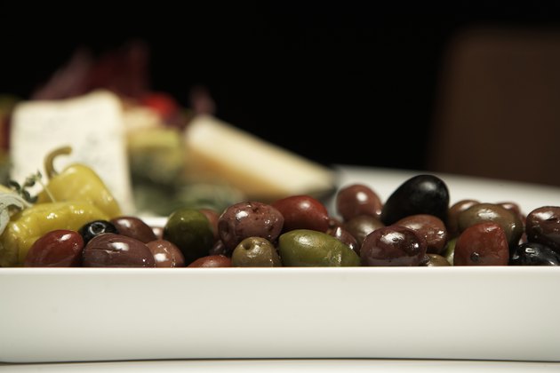 Olives, peppers and cheese on table (focus on olives in foreground)