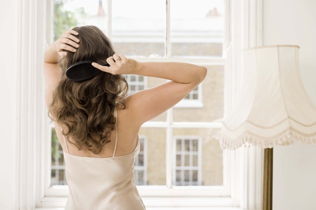 Rear view of woman brushing hair