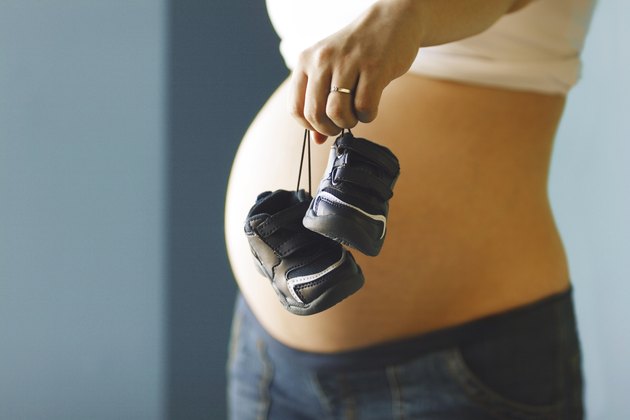 Expecting mother holding baby shoes