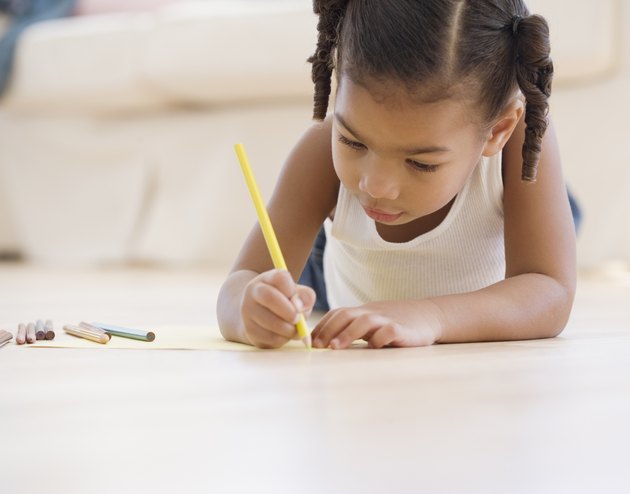 African girl coloring on floor