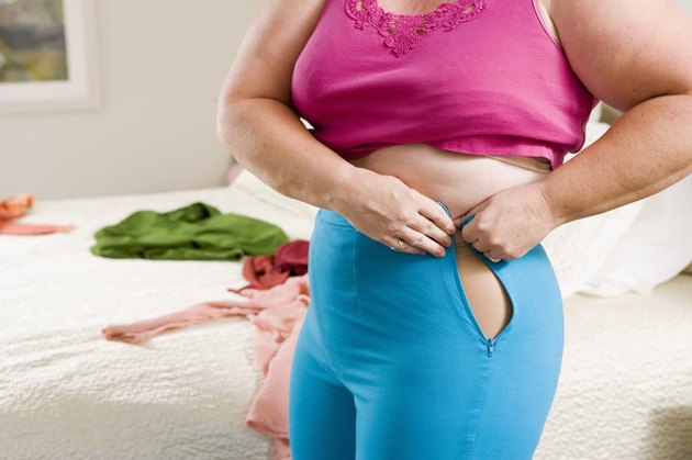 Overweight woman squeezing into small pants