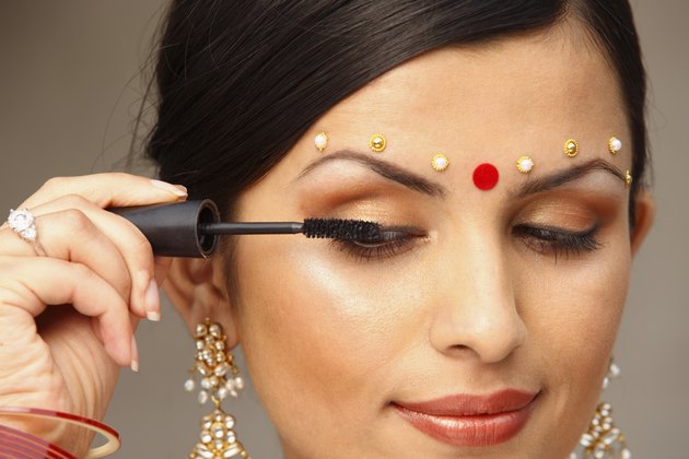 Woman with traditional bindi applying makeup