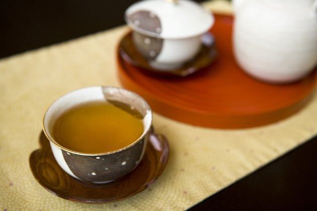 Tea pot and two cups of green tea on table, high angle view, close up, black background, Japan