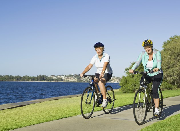 Women riding bicycles by lake