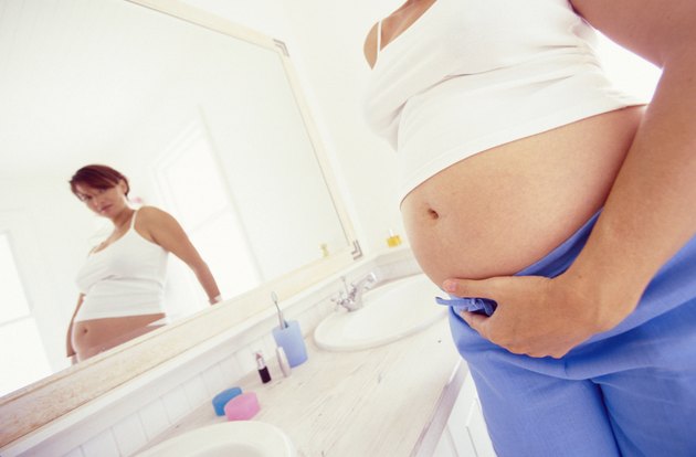 Pregnant woman looking in bathroom mirror