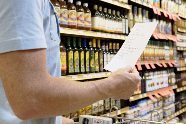 Man with shopping list in supermarket, mid section