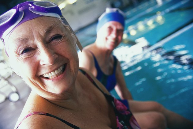 Portrait of two senior women sitting at the edge of a swimming pool