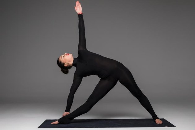 Trikonasana. Beautiful yoga woman practice yoga poses on grey background. Yoga concept.